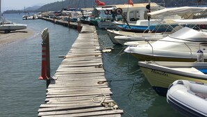Un molo in legno che conduce a un porto turistico con diverse imbarcazioni ormeggiate.