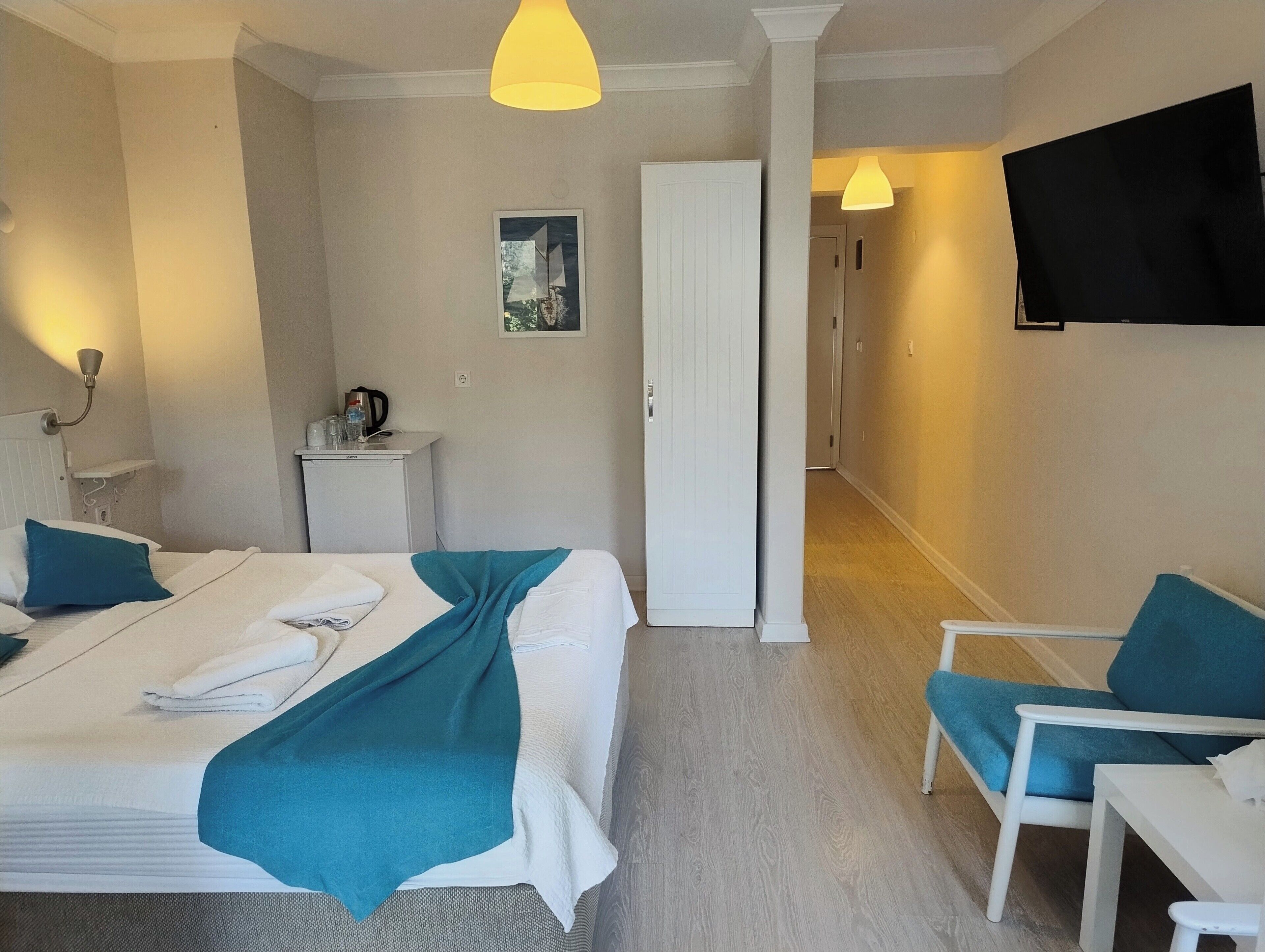 Una habitación de hotel con cama, escritorio, silla, televisor y puerta.