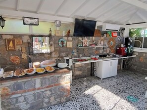 A kitchen with stone walls, a flat-screen TV, and various food items on the counter. -  Göcek Selya Hotel (Fethiye)