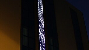 Un edificio con un diseño luminoso vertical en la fachada y un cartel que dice "Sahri Saray Apart".