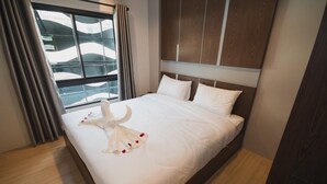 A hotel room with a large bed, a window with curtains, and a view of the outside. - The Y Smart Hotel (Chiang Mai)