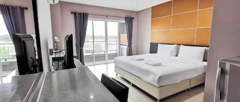 Habitación de hotel moderna con una cama grande, un escritorio con silla y vistas al exterior.