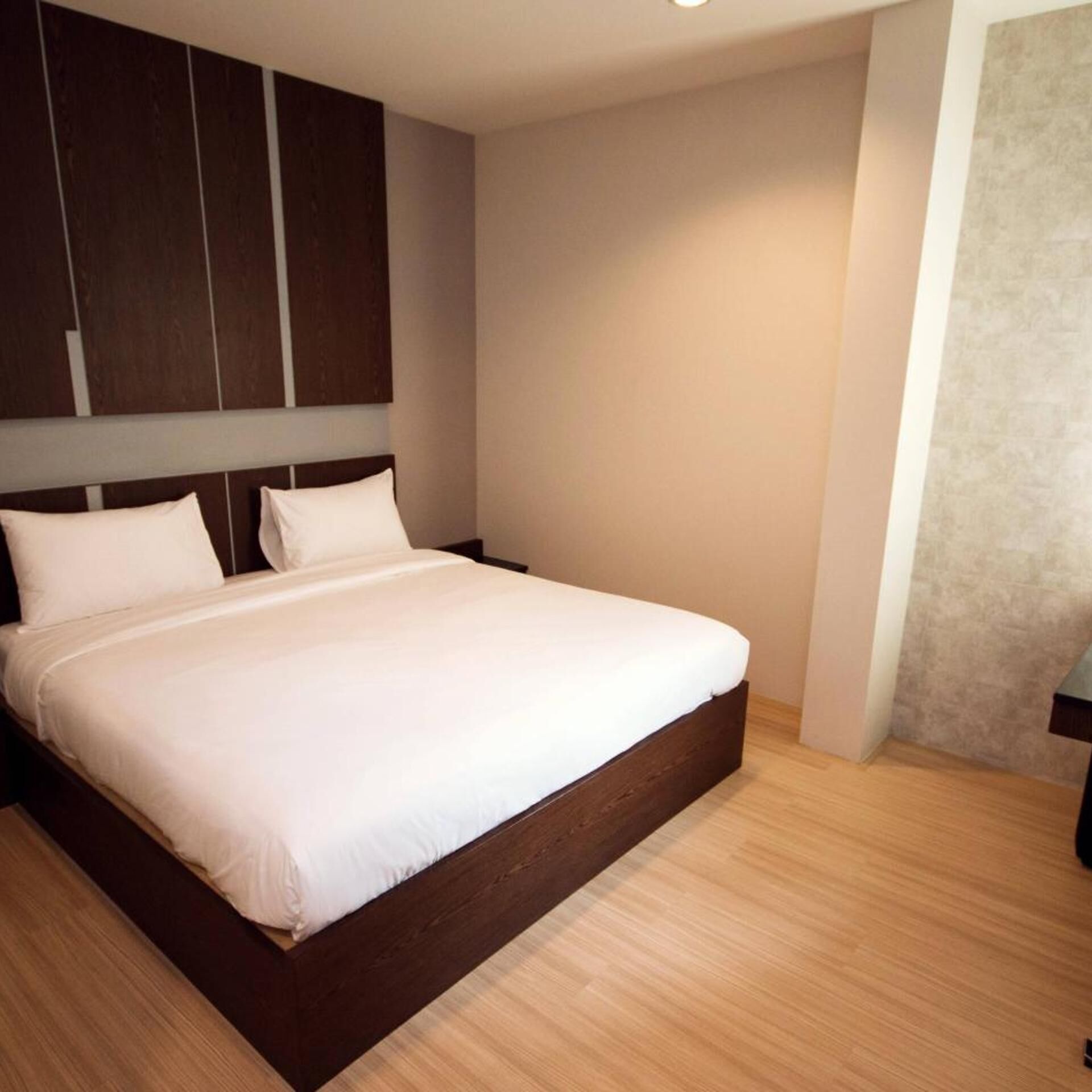 A bedroom with a large bed, wooden headboard, and built-in wardrobe.