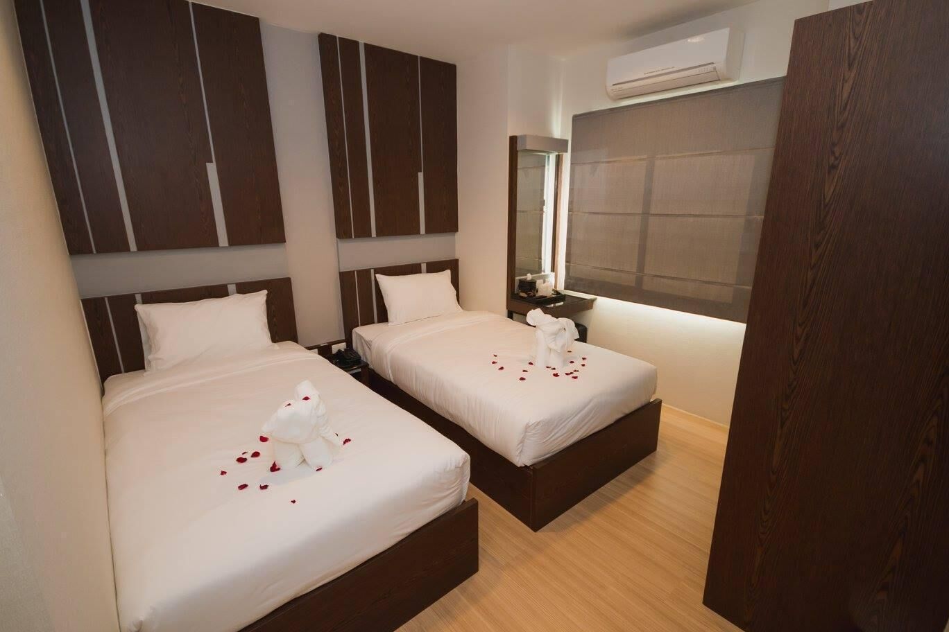 Habitación de hotel con dos camas, un espejo, una ventana y un equipo de aire acondicionado.
