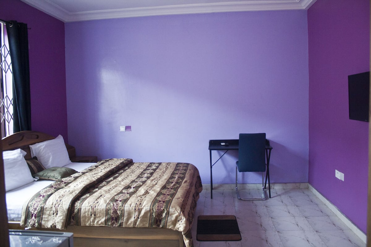 Um quarto com uma cama, uma escrivaninha e uma cadeira.