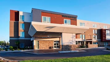 A modern hotel with a brick facade, large windows, and a covered entrance area.