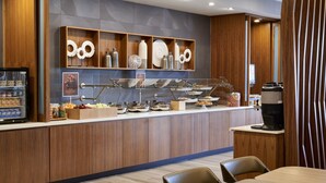 A modern breakfast bar with a variety of food items and a coffee machine. - Springhill Suites Grand Rapids West (Grandville)