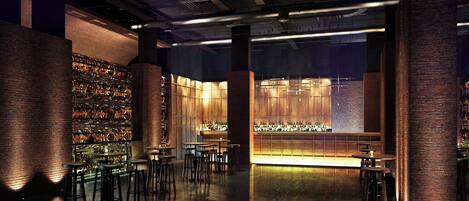 Un área de bar moderna con paredes de ladrillo, mostrador de madera y varios taburetes.