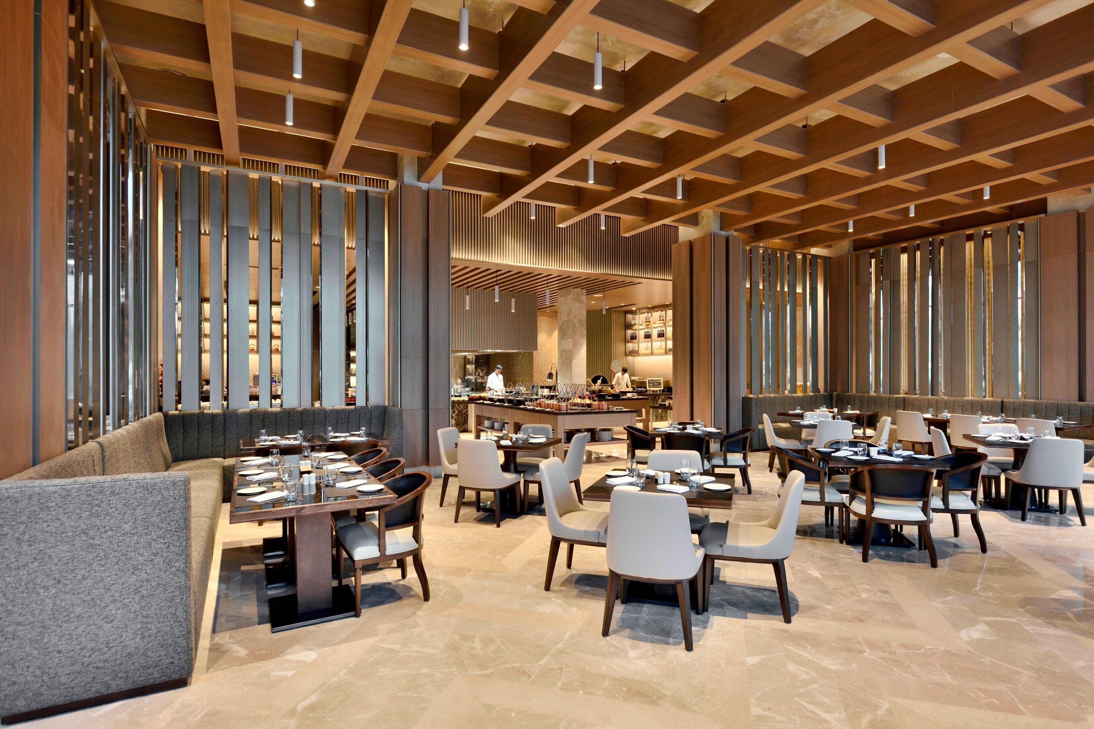A spacious restaurant with high ceilings, wooden beams, and a variety of seating arrangements including tables and chairs.
