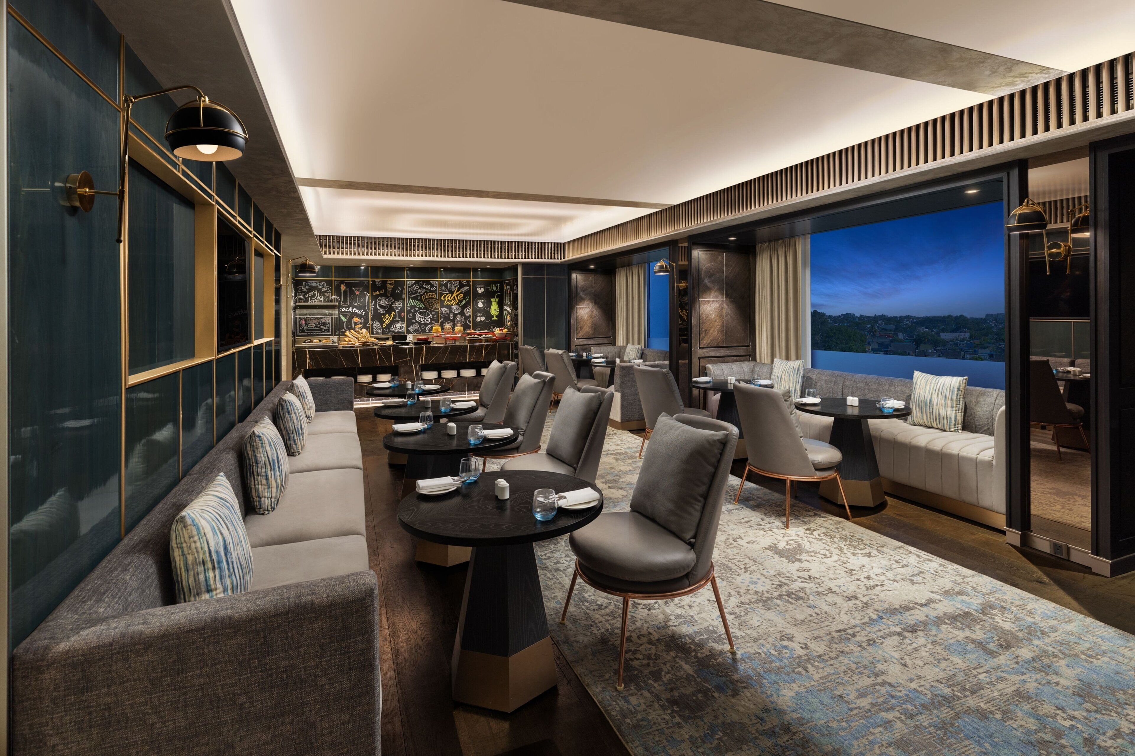 A modern lounge area with seating, tables, and a bar.