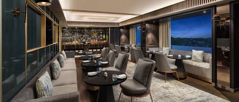 A modern lounge area with seating, tables, and a bar.