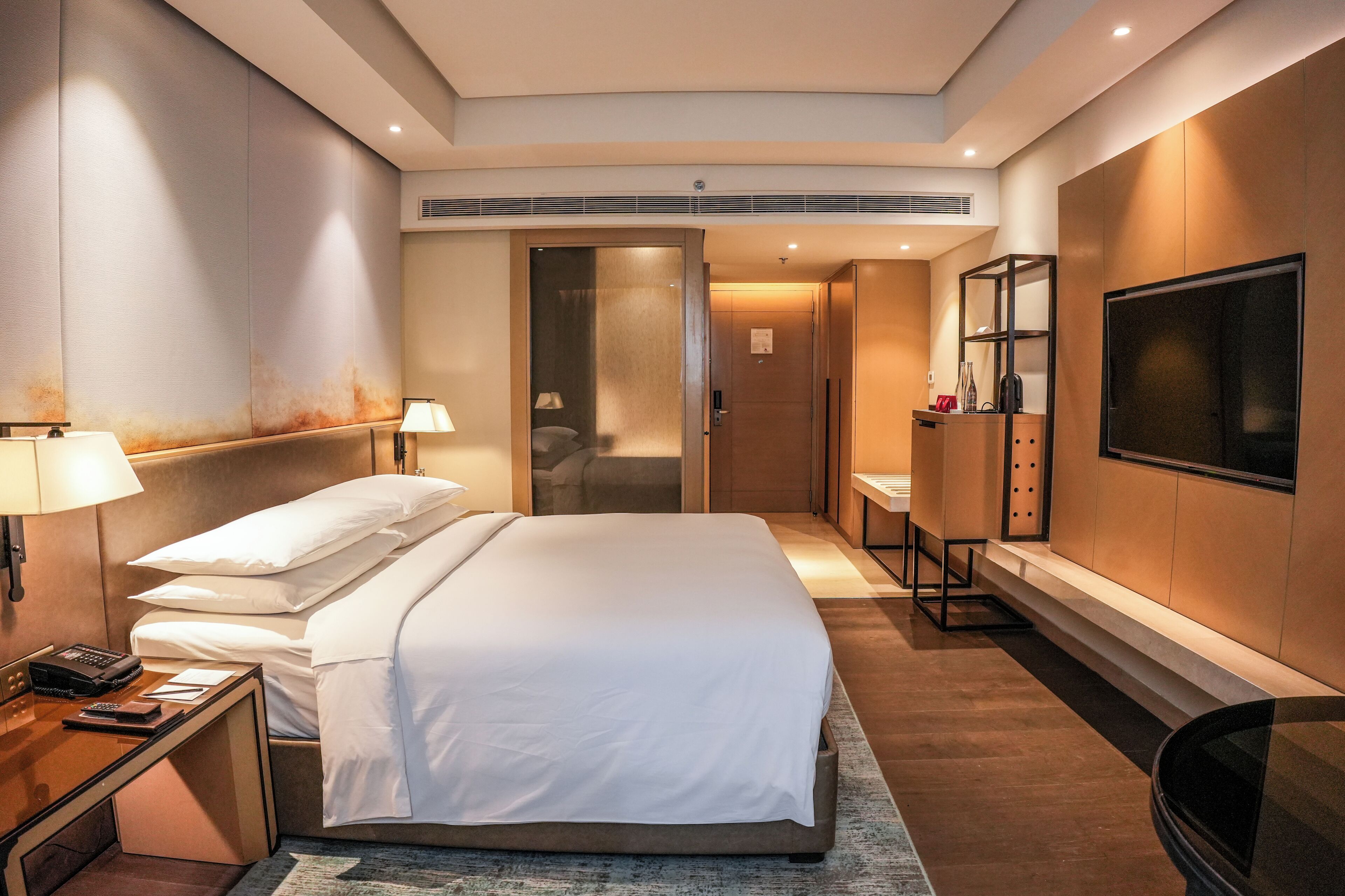 Una camera d'albergo moderna con un letto grande, comodini, una scrivania e una TV.