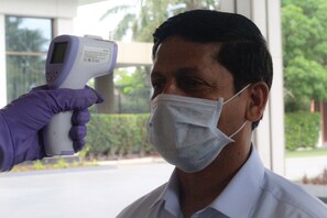 Una persona siendo examinada por un dispositivo portátil, posiblemente para medición de temperatura o detección de salud.