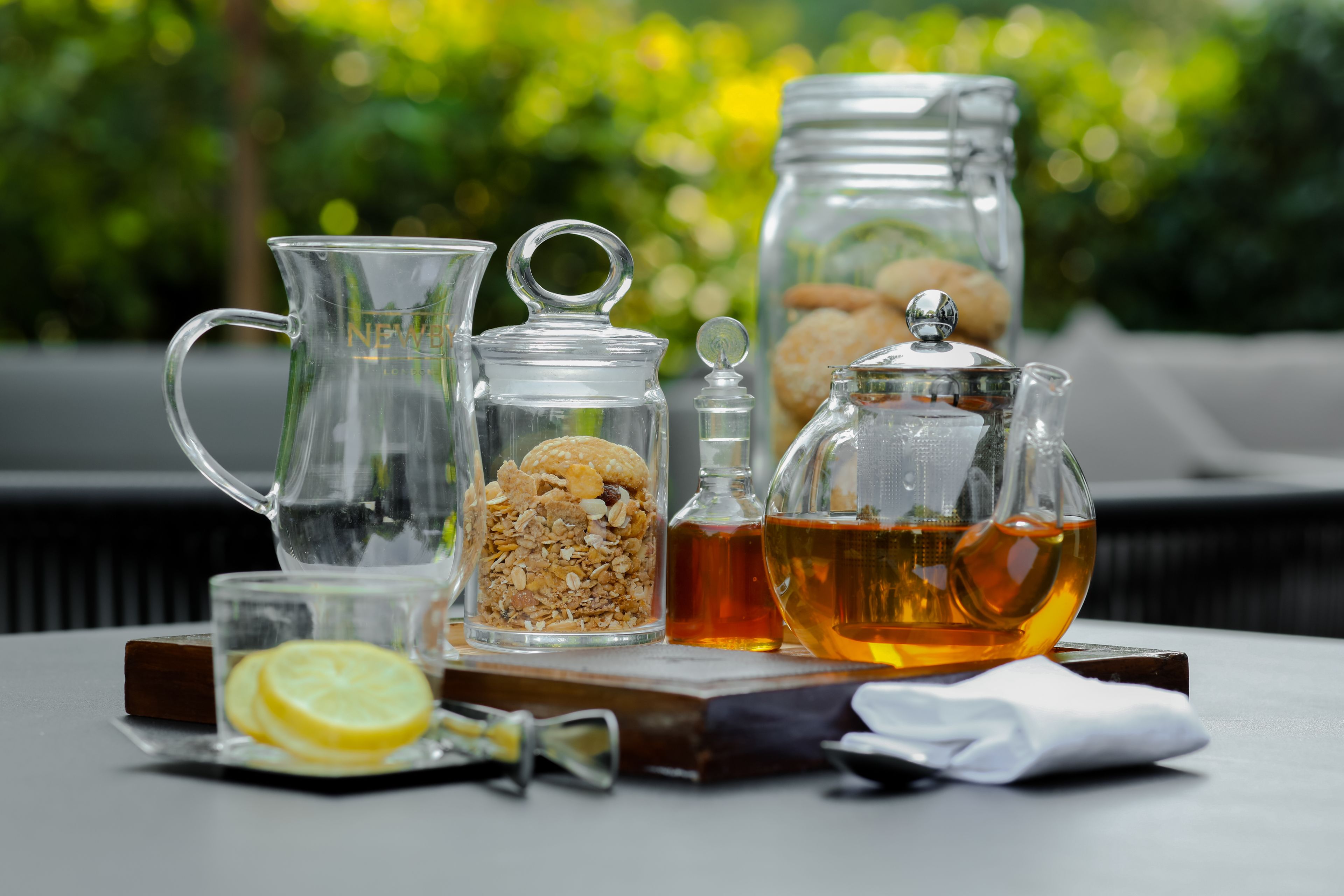 Een tafel met een karaf, een glazen pot met deksel, een glas met een citroenpartje en een fles honing.