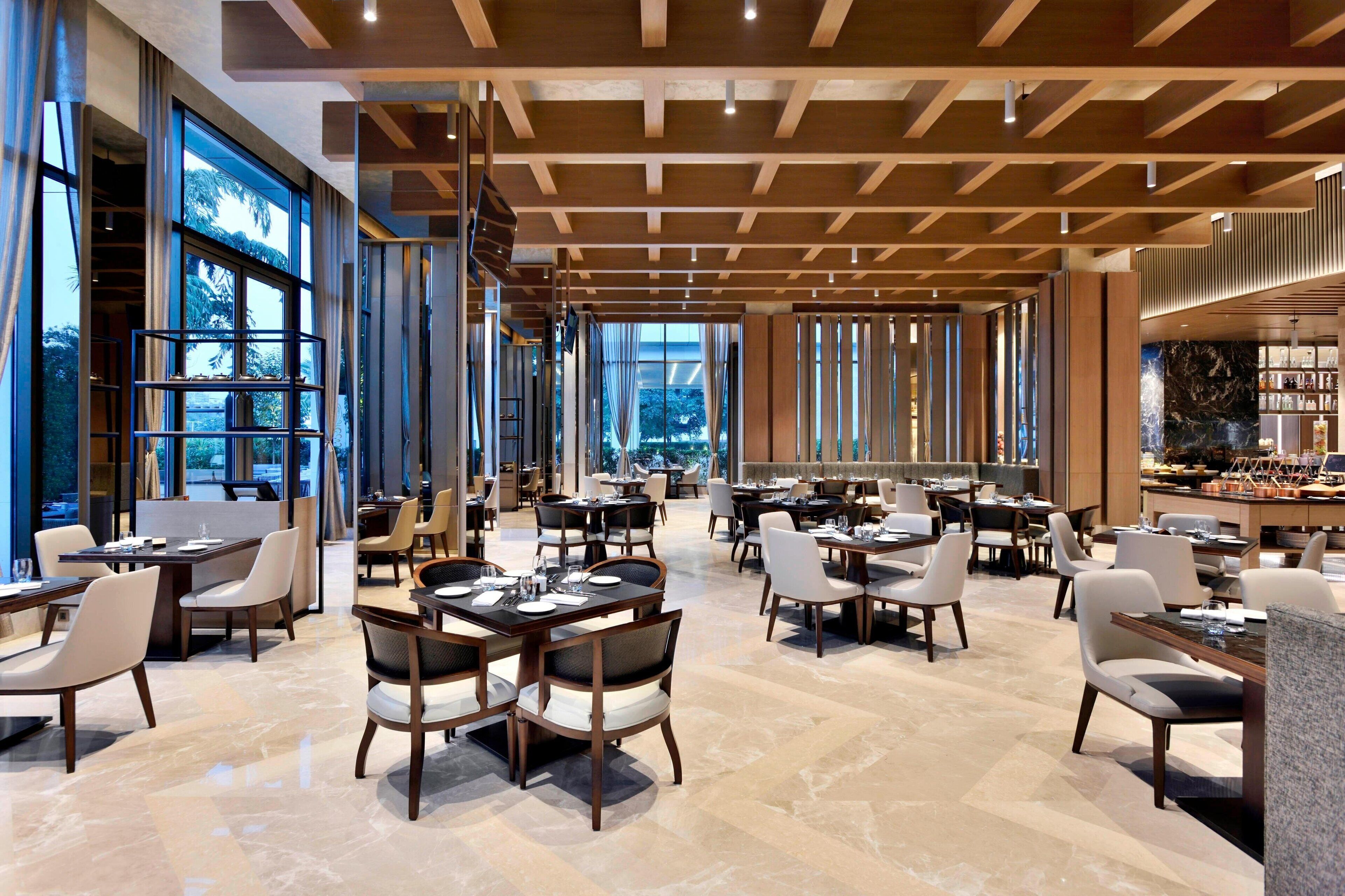 A spacious restaurant with high ceilings, large windows, and modern furniture.