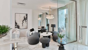 A modern living room with a marble floor, a large abstract painting, and a glass partition with a view. - Ezeretz SPA Hotel (Blagoevgrad)