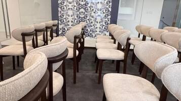 A conference room with rows of chairs, a patterned wall, and a glass partition.