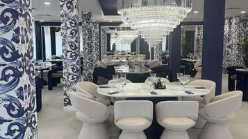 Un comedor moderno con una lámpara de araña grande, columnas blancas y azules con diseño y mobiliario contemporáneo.
