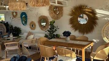 A room with wicker furniture, a wooden dining table, and hanging rattan lamps.