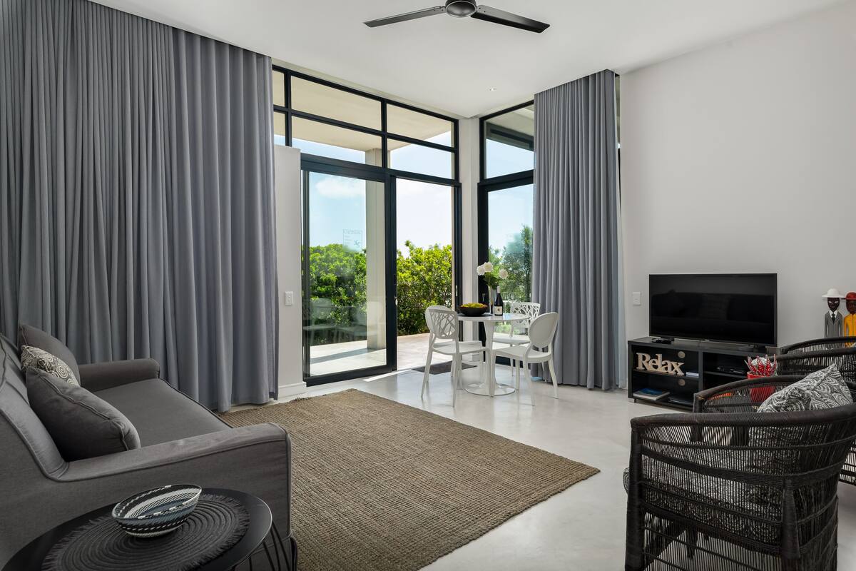 Uma sala de estar moderna com um sofá, um rack para TV e um espaço de jantar.