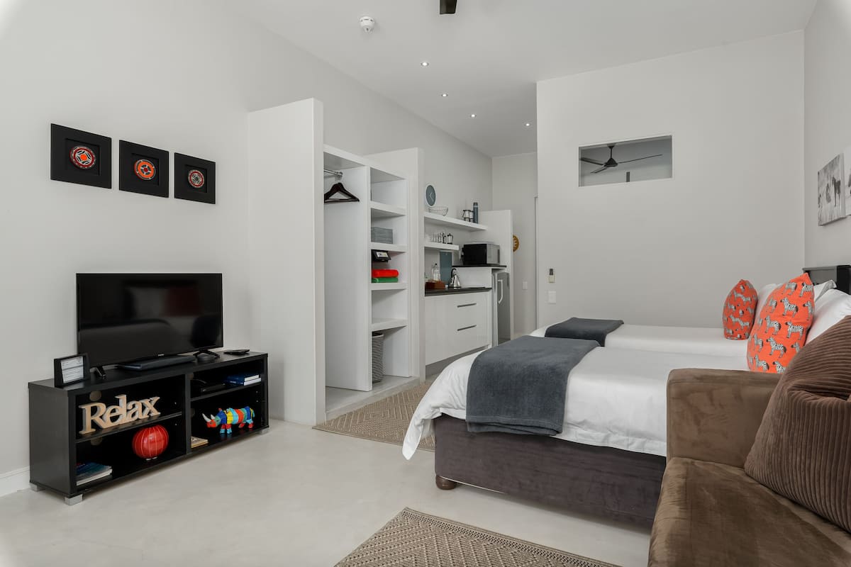 Quarto moderno com televisão, sofá, cama e closet espaçoso.