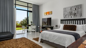 A modern bedroom with a large bed, a desk, and a TV. - Sunset Splendour Guesthouse (Cape Town)