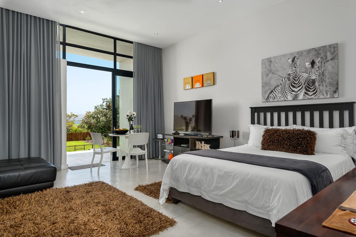 Quarto moderno com uma cama grande, uma escrivaninha e uma televisão.