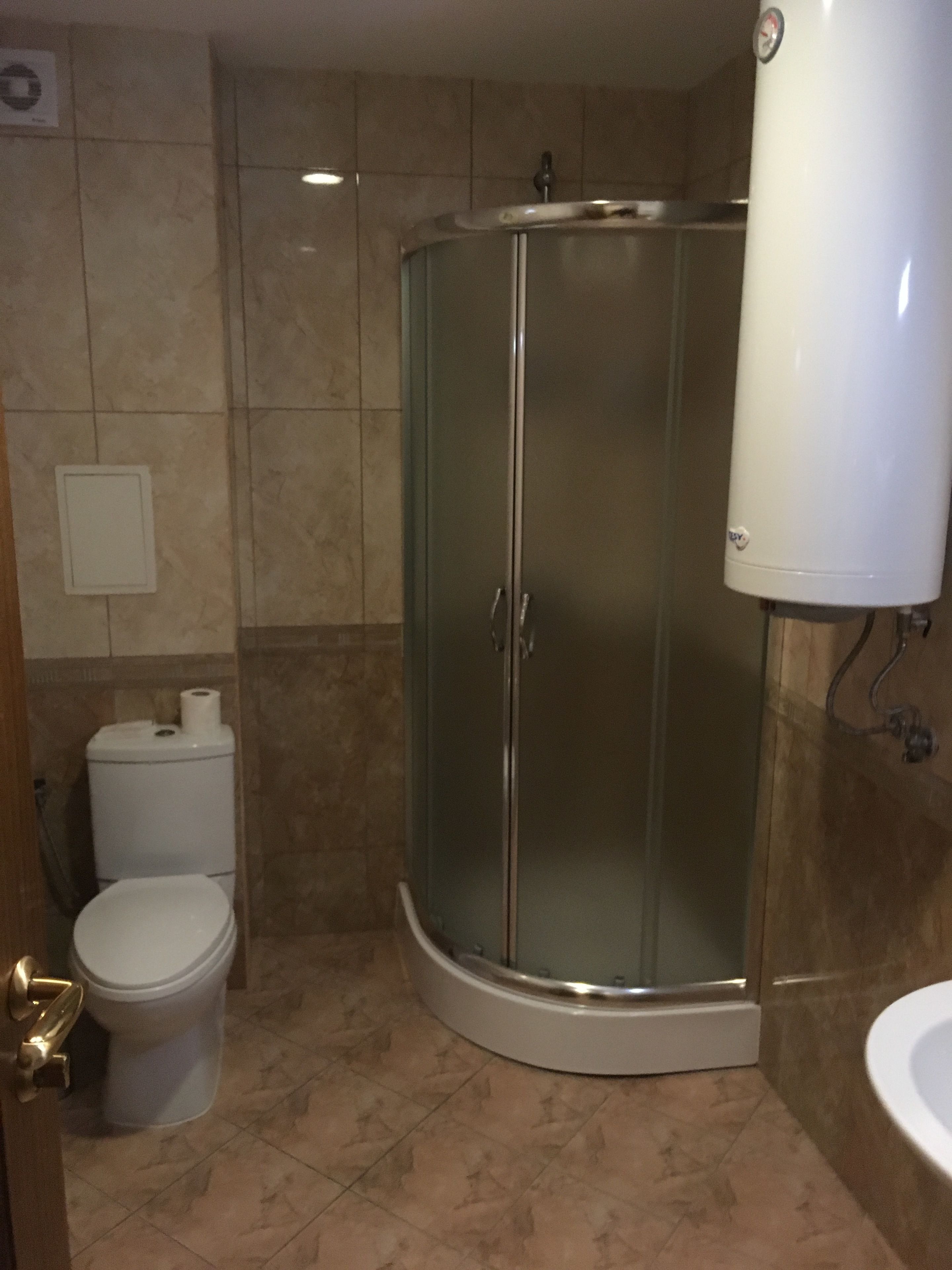 Un baño con ducha de vidrio, inodoro y lavamanos.