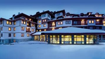Un hotel de varios pisos con techo nevado y vestíbulo con paredes de vidrio.