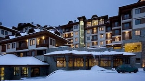 Et hotel med flere etager, altaner og store vinduer, omgivet af sne.
