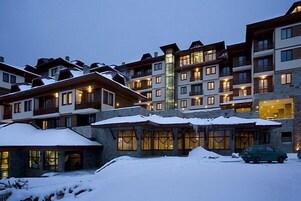 Un hotel de varios pisos con balcones y ventanas amplias, rodeado de nieve.