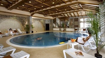 Una piscina interior con sillas de descanso y plantas en macetas.