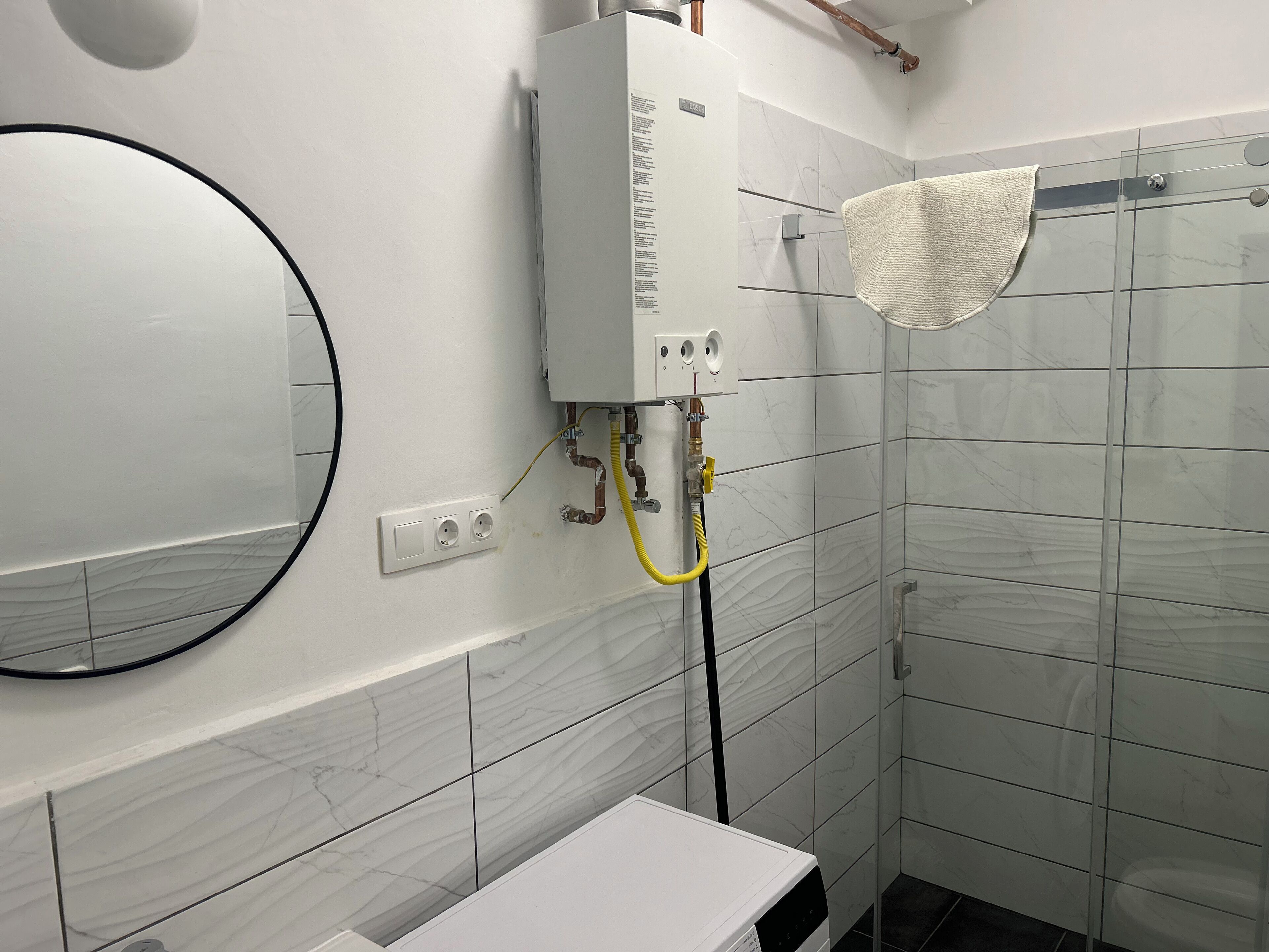 A bathroom with a white toilet, a mirror, a towel rack, and a shower with a glass door.