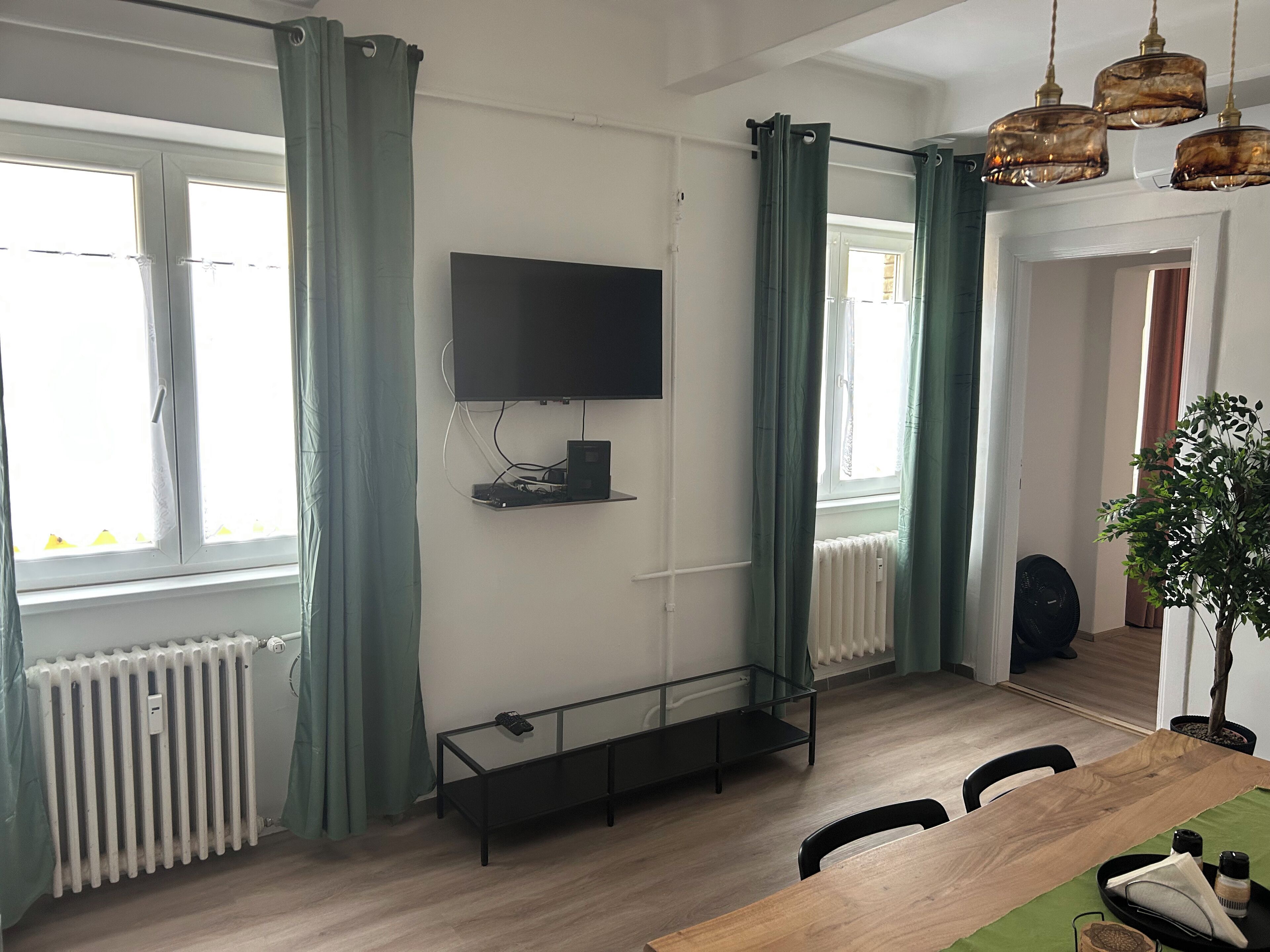 Un saló modern amb un televisió de pantalla plana penjada a la paret, una taula de centre de vidre i una taula de menjador amb cadires.