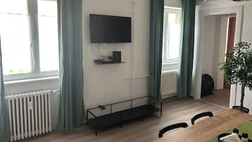 Un saló modern amb un televisió de pantalla plana penjada a la paret, una taula de centre de vidre i una taula de menjador amb cadires.
