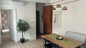 Un coin repas avec une table en bois, des chaises noires, une plante en pot et des luminaires suspendus.