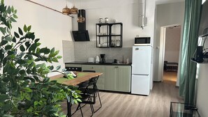 Une cuisine moderne avec une table en bois, des armoires vertes et un réfrig érateur blanc.