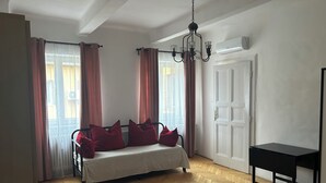 Une chambre à coucher avec un lit, un bureau, un lustre et une fenêtre avec des rideaux.