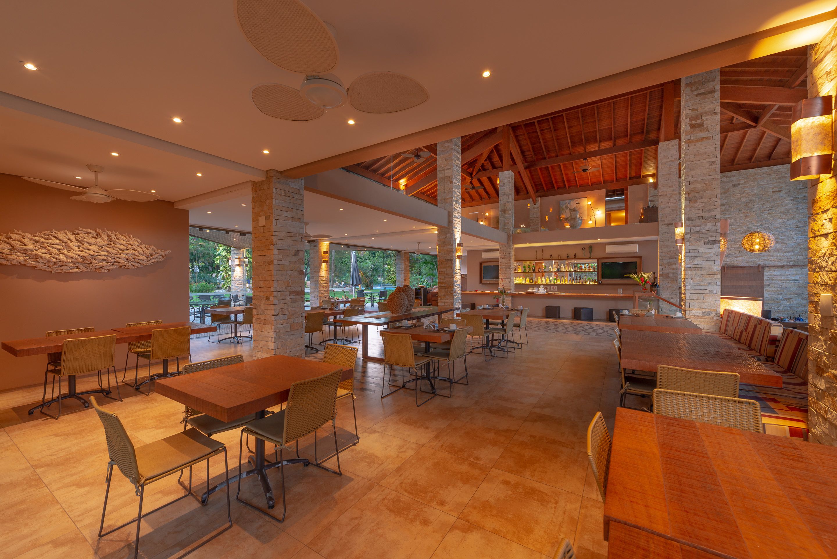A spacious indoor area with multiple tables and chairs, a bar area, and a view of the outdoors.