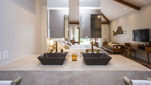 Een moderne badkamer met twee zwarte wasbakken, een spiegel en een gele zeepdispenser.