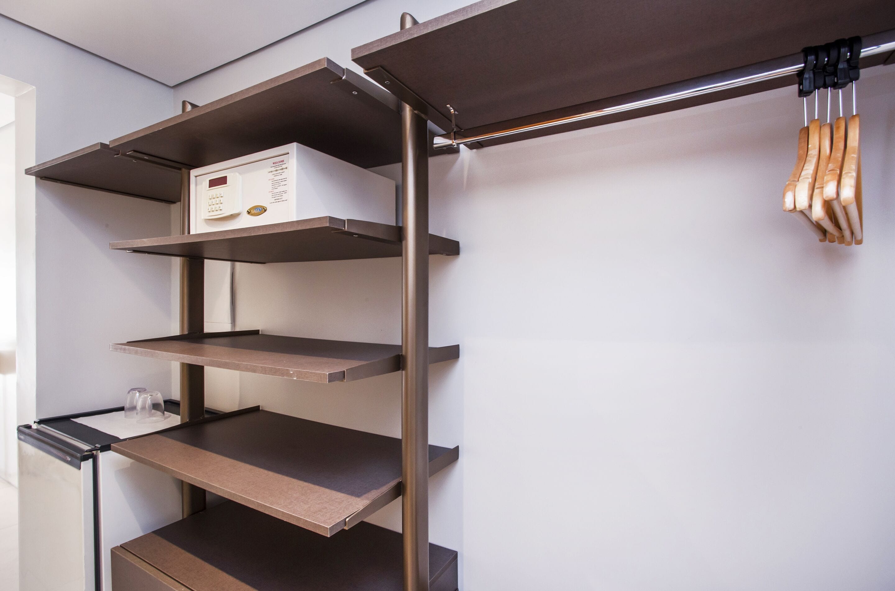 A metal shelving unit with multiple levels, a microwave, and a hanging rack with utensils.