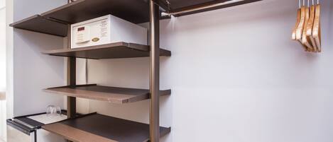 A metal shelving unit with multiple levels, a microwave, and a hanging rack with utensils.