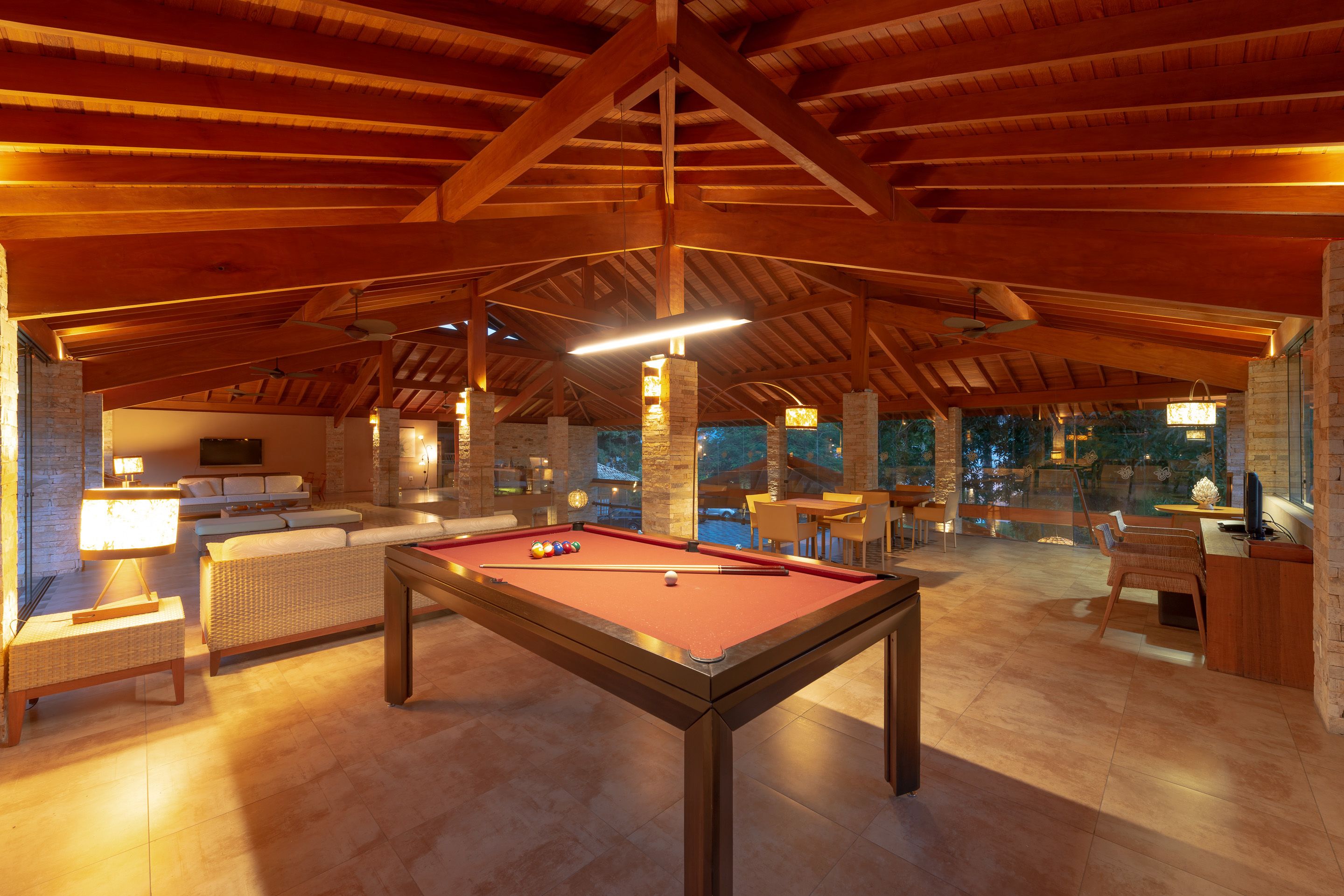 A spacious indoor area with a pool table, seating, and a view of the outdoors.