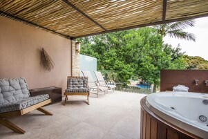 Un espacio al aire libre techado con un jacuzzi, sillones de descanso y vistas a una piscina.