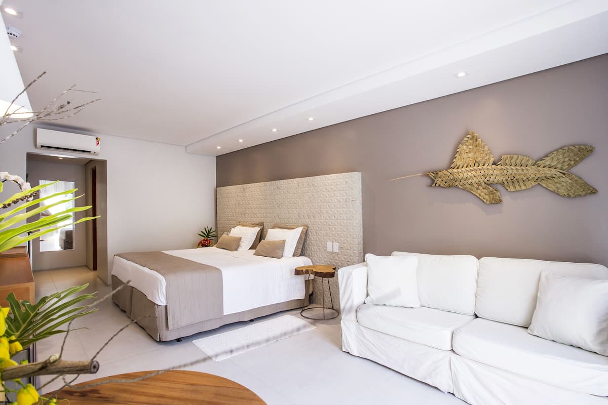 Un dormitori modern amb un llit gran, un sofà blanc i una peça decorativa a la paret.