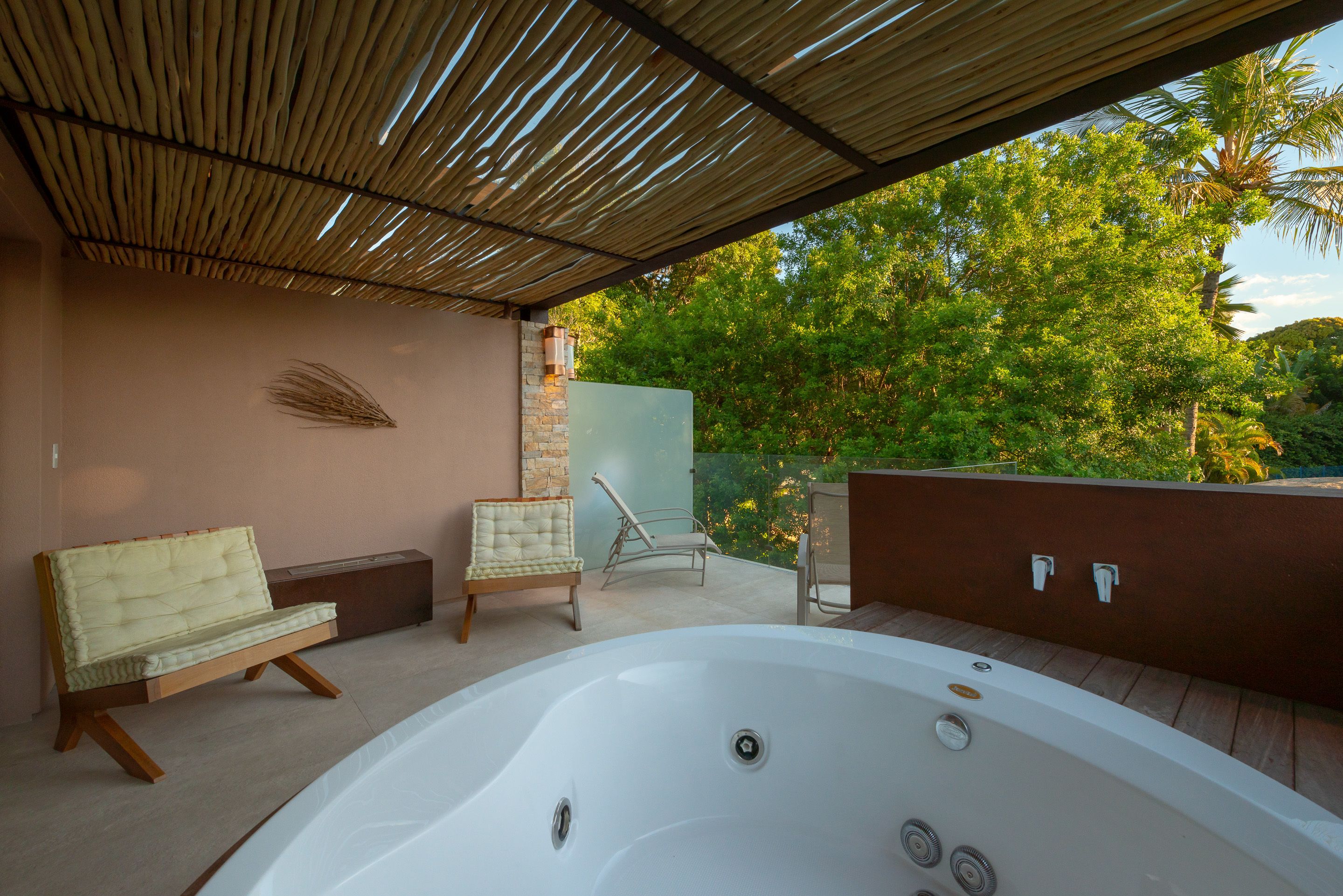 Un área de spa con una bañera de hidromasaje, un banco acolchado y una silla de descanso.
