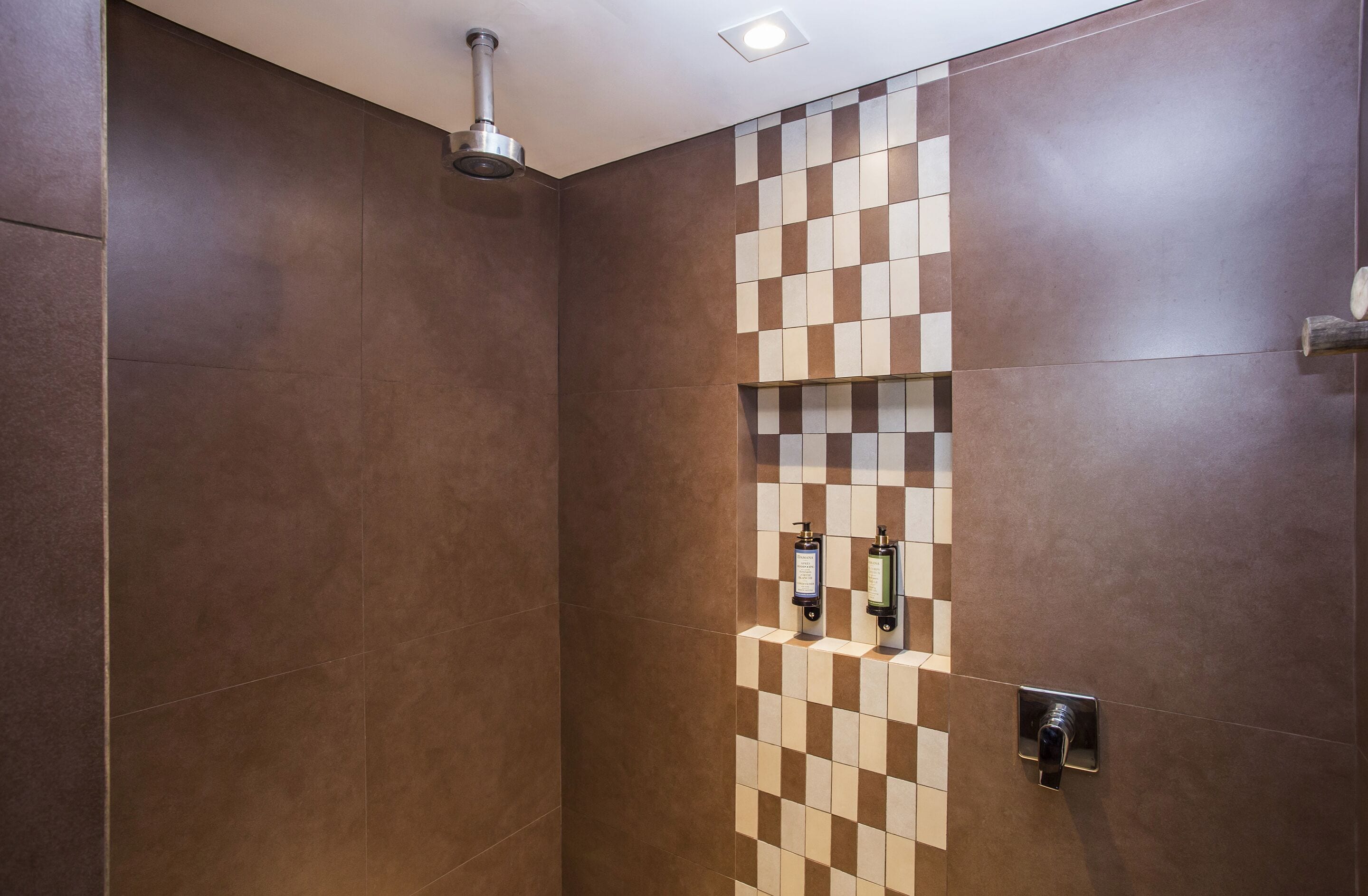 A modern bathroom with a checkered tile wall, a showerhead, and a digital control panel.
