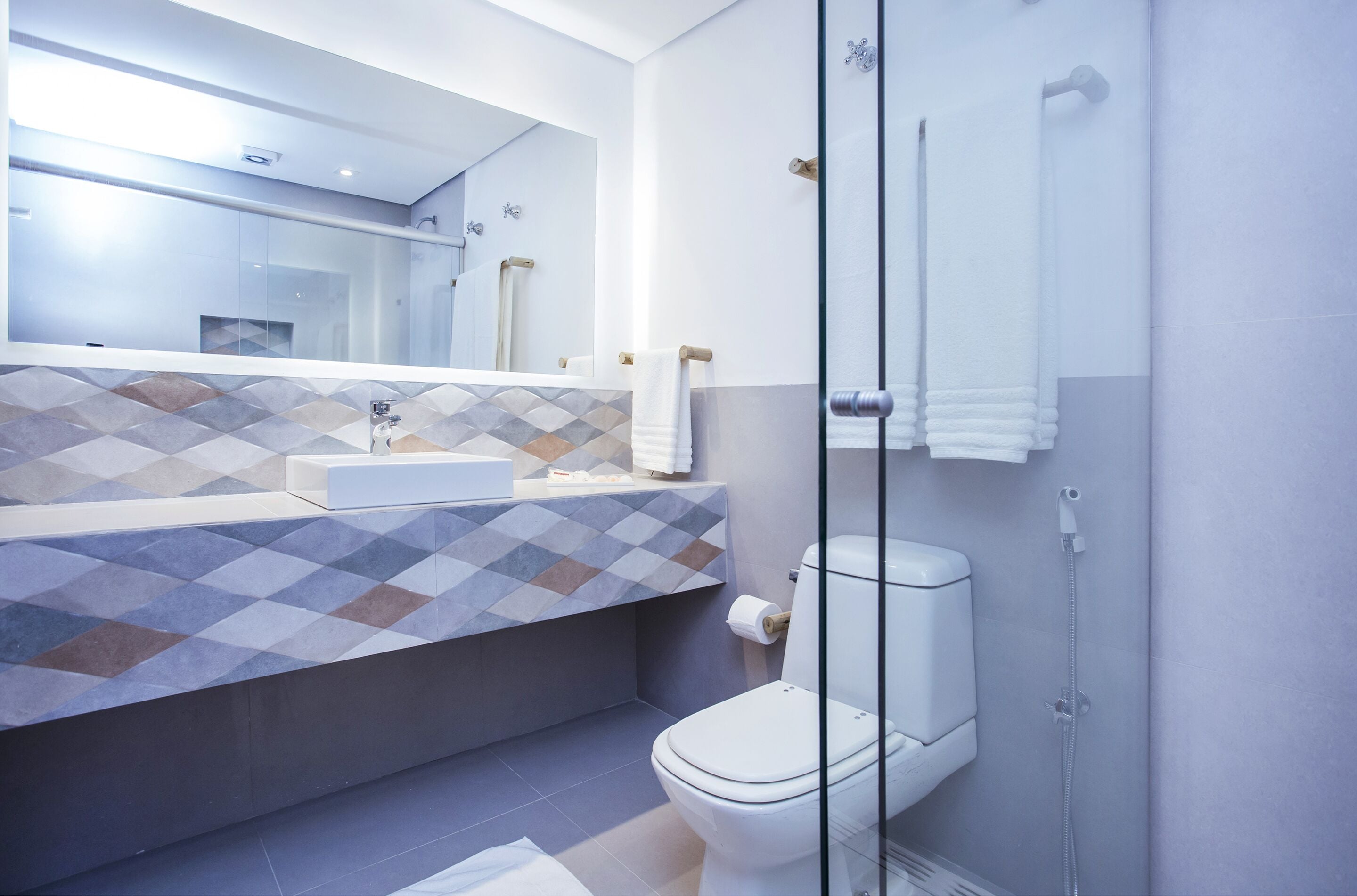 A modern bathroom with a glass shower enclosure, a white toilet, and a tiled vanity.