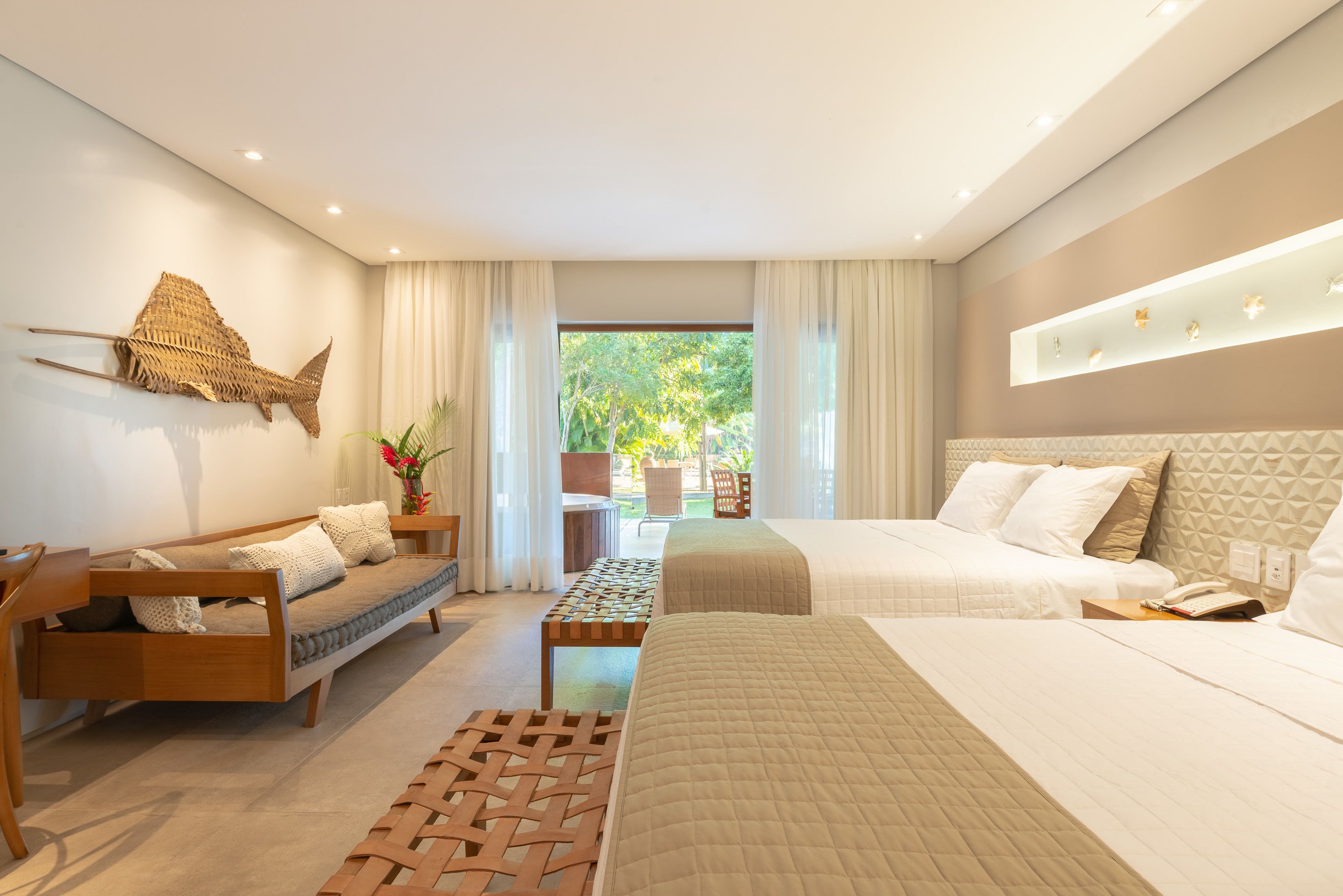 Quarto de hotel moderno com sofá, cama, mesa pequena e vista para o exterior.