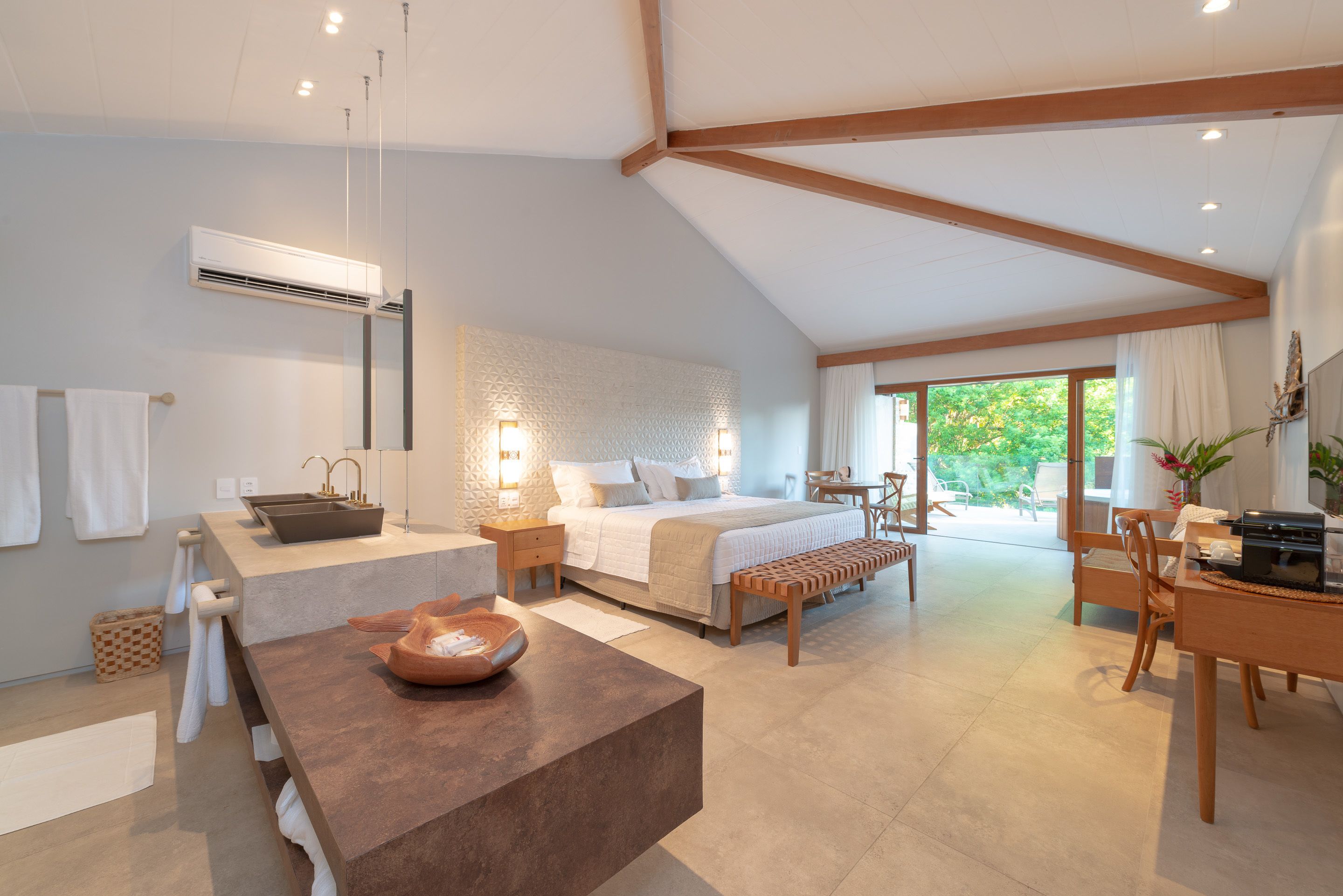A modern bedroom with a large bed, bedside tables, a desk, and a bench.